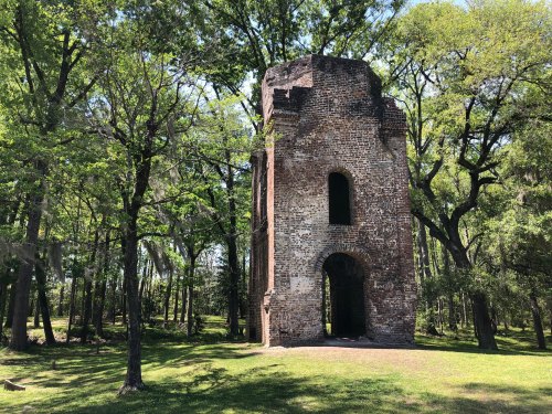 A tall, weathered brick structure surrounded by lush green trees in a serene park setting.