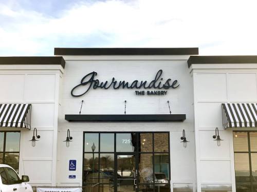 Sign for "Journandise The Bakery" on a storefront with striped awnings and large glass windows.