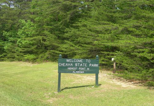 Sign welcoming visitors to Cheaha State Park, the highest point in Alabama, surrounded by green trees.