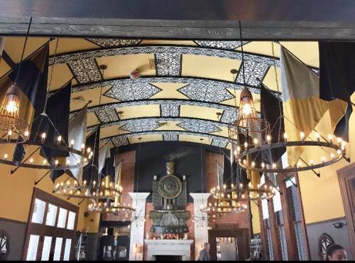 Interior of a grand hall featuring high ceilings, decorative chandeliers, and banners hanging from the walls.