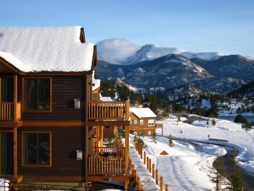 Snow-covered mountains in the background with wooden cabins and a winding road in a winter landscape.