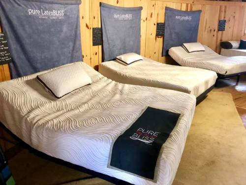 Three adjustable beds with wavy-patterned mattresses in a wooden room, featuring a soft area rug.