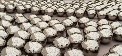 A close-up view of numerous shiny, reflective spheres arranged in a grid pattern, reflecting light and surroundings.