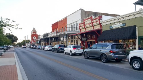 A charming street lined with historic buildings and parked cars, showcasing a small-town atmosphere.
