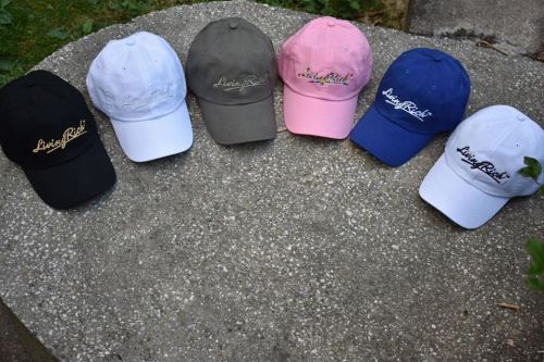 A collection of six caps in black, white, gray, pink, blue, and navy, displayed on a stone surface.