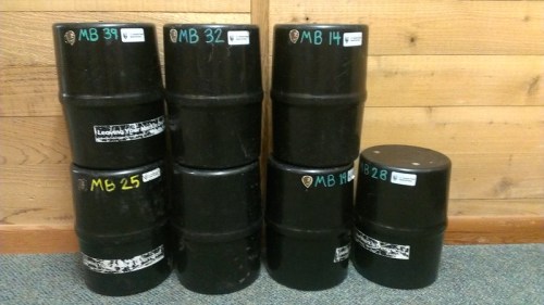 A stack of black barrels labeled with numbers on a wooden background.