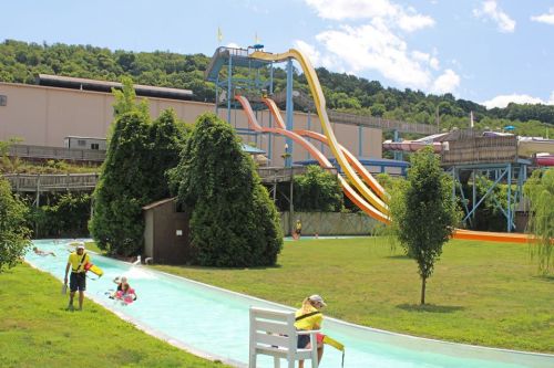 A water park scene featuring colorful slides, a lazy river, and people enjoying the sun on a clear day.