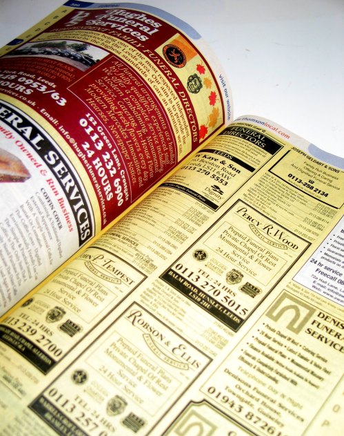 Open magazine page featuring various advertisements and listings for services, including funeral and general services.