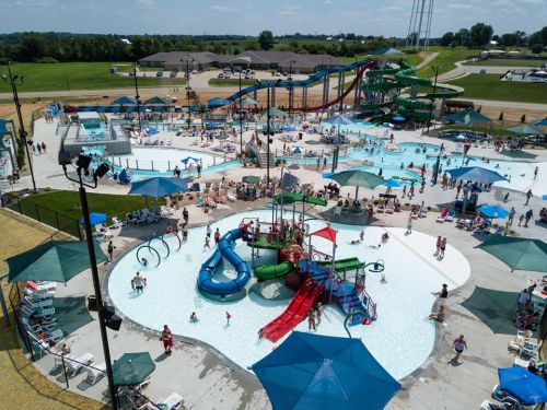 Aerial view of a busy water park with slides, pools, and families enjoying the sunny day.