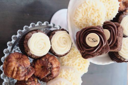 A variety of decorated cupcakes and pastries on a glass stand, featuring chocolate and vanilla frosting.