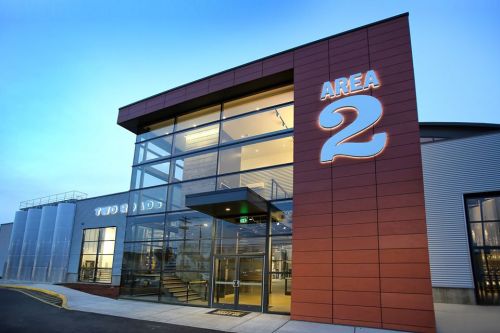 Modern building exterior with large glass entrance and "AREA 2" signage, set against a twilight sky.
