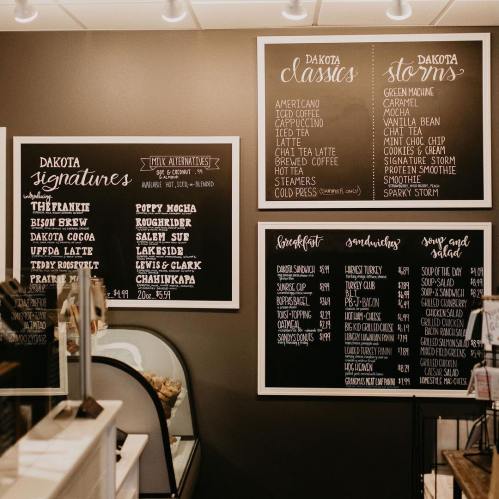 Chalkboard menu displaying drinks and food options at Dakota café, featuring signatures, classics, and breakfast items.