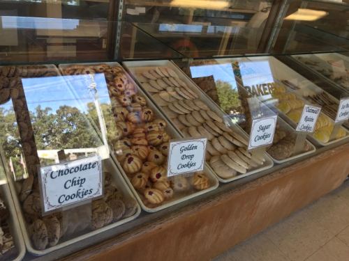 A display case filled with various cookies, including chocolate chip, golden drop, sugar, and almond lace cookies.