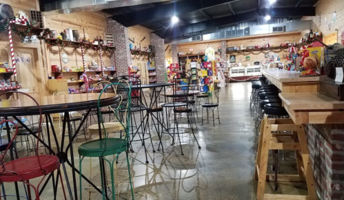 A cozy shop interior with colorful chairs, festive decorations, and shelves filled with various products.