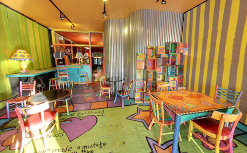 Colorful cafe interior with vibrant walls, playful furniture, and whimsical decor, creating a cheerful atmosphere.