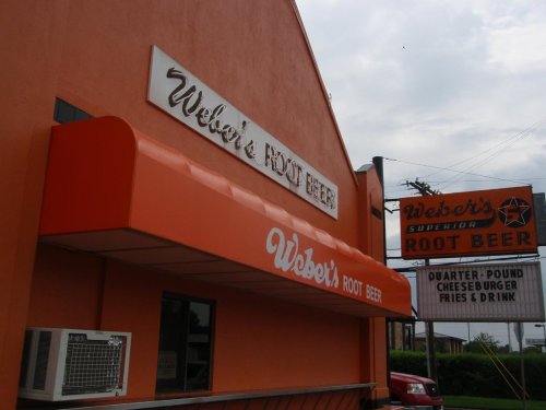 Signage for Weber's Root Beer featuring an orange awning and a menu board with food options.