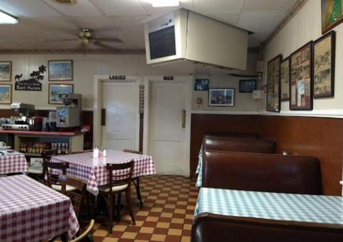 Interior of a diner with checkered tablecloths, booths, and signs for "Ladies" and "Men" restrooms.