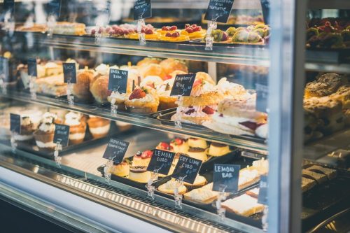 A display case filled with various pastries and desserts, each labeled with small black signs.