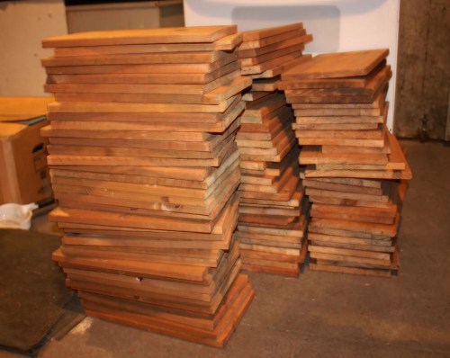 A stack of wooden boards neatly piled in a workshop or storage area.