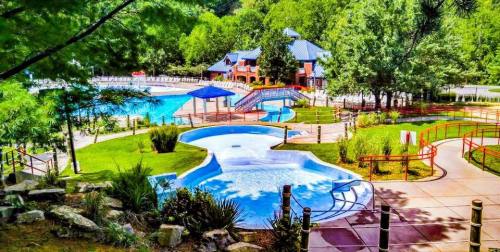 A scenic view of a resort pool area surrounded by greenery, featuring slides and pathways for visitors.