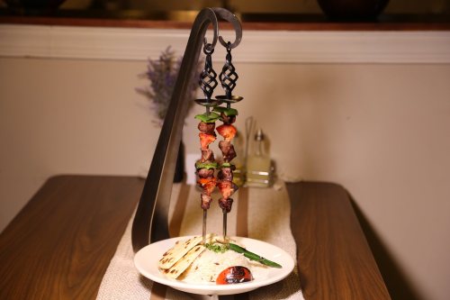 A stylish display of skewers with grilled meat and vegetables, served with rice and flatbread on a wooden table.