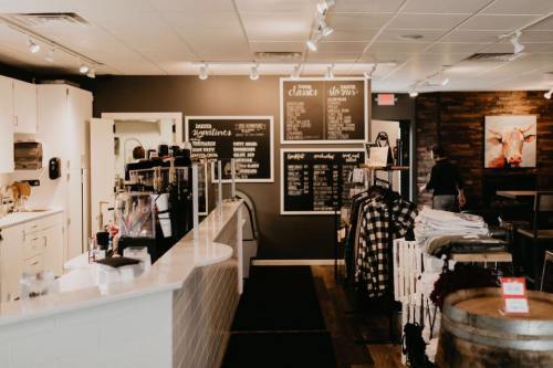 A cozy café interior with a counter, menu boards, and merchandise displays, featuring warm lighting and wooden accents.