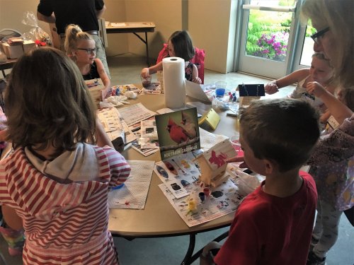 Children engaged in a creative art project at a table, surrounded by various craft materials and colorful decorations.