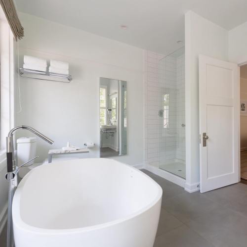 Modern bathroom featuring a freestanding tub, glass shower, and minimalist decor in soft colors.