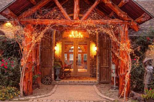 A rustic entrance with wooden beams, warm lights, and floral decorations, creating a welcoming atmosphere.