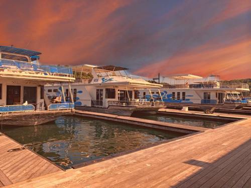Houseboats docked at a marina under a vibrant sunset sky, reflecting on the calm water.