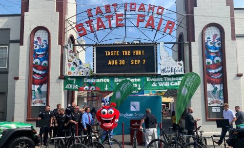 A colorful entrance to the East Idaho State Fair with a mascot, bicycles, and event banners.