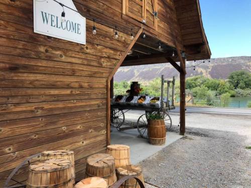 A rustic wooden building with a "Welcome" sign, featuring barrels and a table with decorative items outside.
