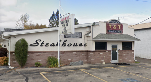Exterior of Annie's T&T Steakhouse, featuring a sign and a brick facade with parking in front.