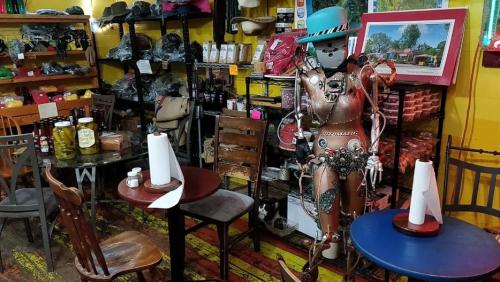 A quirky shop interior featuring a robot mannequin, colorful tables, and various items on display.