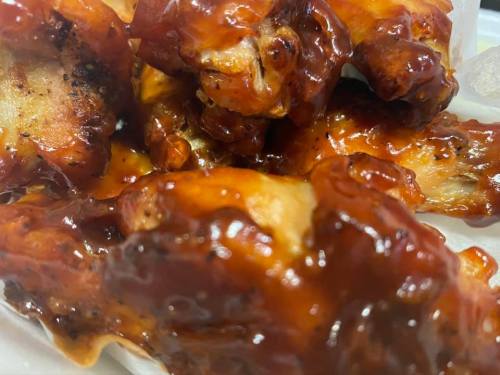 Close-up of glazed chicken wings, coated in a rich, sticky barbecue sauce.