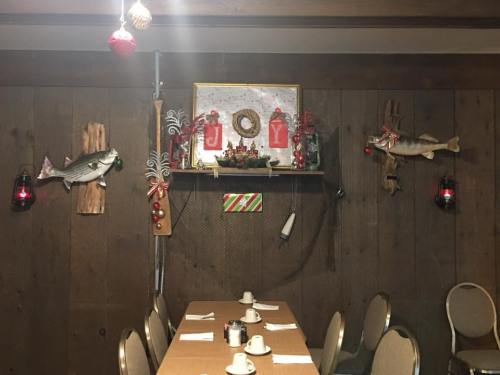 A festive dining area with a wooden table, holiday decorations, and fish mounted on the walls.