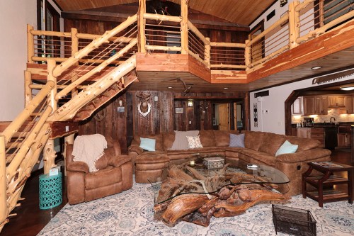 Cozy living room with a large sectional sofa, wooden accents, and a staircase leading to an upper level.