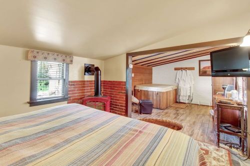 Cozy bedroom with a striped bedspread, brick wall, and a view of a spa area with a hot tub and bathrobes.