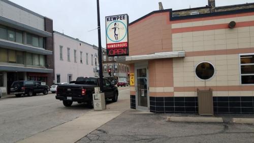 A Kewpee Hamburgers restaurant with a bright sign, a truck parked outside, and a street view of nearby buildings.