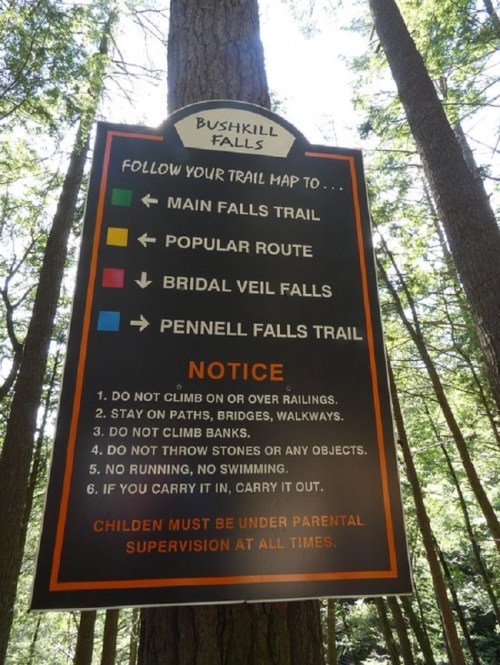 Sign at Bushkill Falls with trail map and safety notices, including rules for visitors and parental supervision requirements.