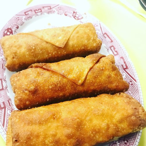 Three golden-brown, crispy egg rolls arranged on a decorative plate.