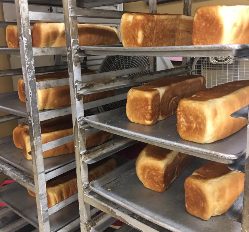Freshly baked loaves of bread cooling on metal racks in a bakery.