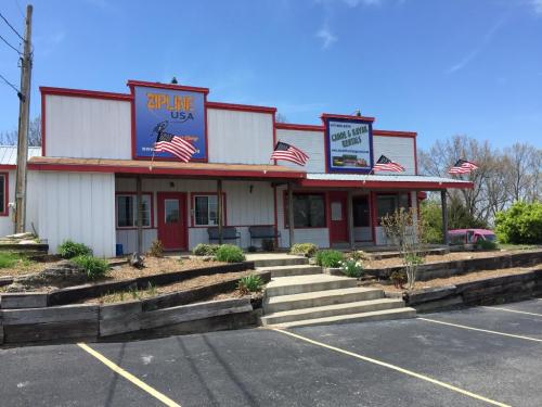 A building with a sign for "Zipline USA," featuring American flags and a landscaped entrance on a sunny day.