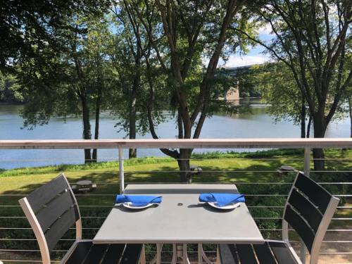 A table set for two on a balcony overlooking a serene lake surrounded by trees.