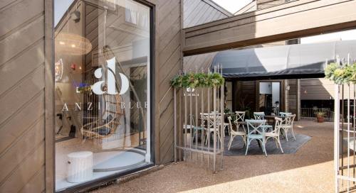 Exterior view of Anzi Blue, featuring a modern entrance and outdoor seating area with festive decor.