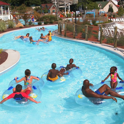 People enjoying a lazy river at a water park, floating on inner tubes in a bright blue pool.