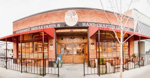 Exterior of Maple Counter Café, featuring a brick facade, red awnings, and large windows showcasing a cozy dining space.