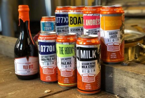 A collection of colorful craft beer cans arranged on a wooden surface, showcasing various styles and labels.