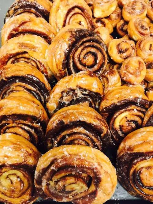 A close-up of freshly baked cinnamon rolls, showcasing their golden-brown swirls and glossy glaze.