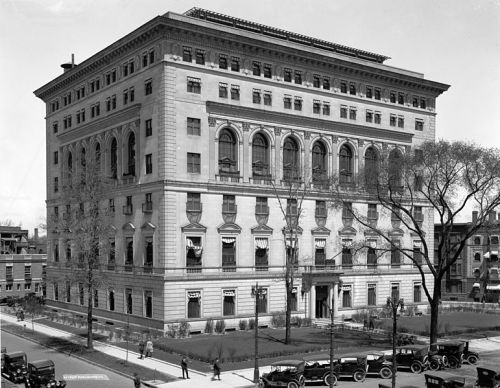 Historic black-and-white photo of a grand, multi-story building with large windows and classic architectural details.